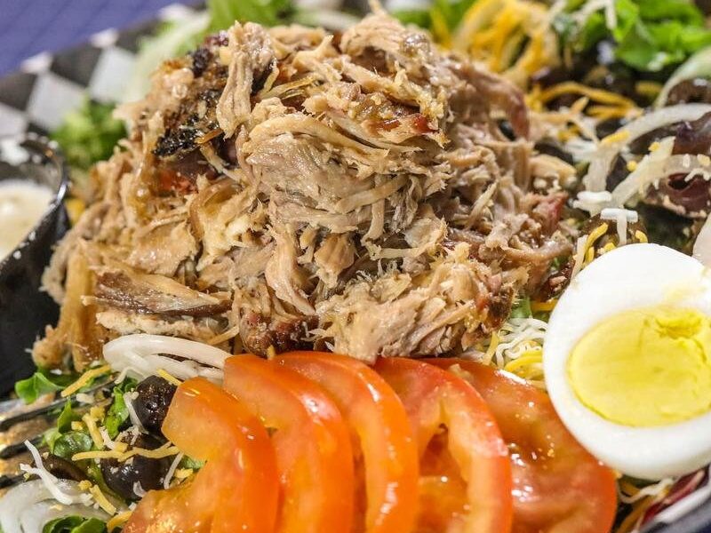 BBQ salad topped with pulled pork, egg, tomato and cheddar